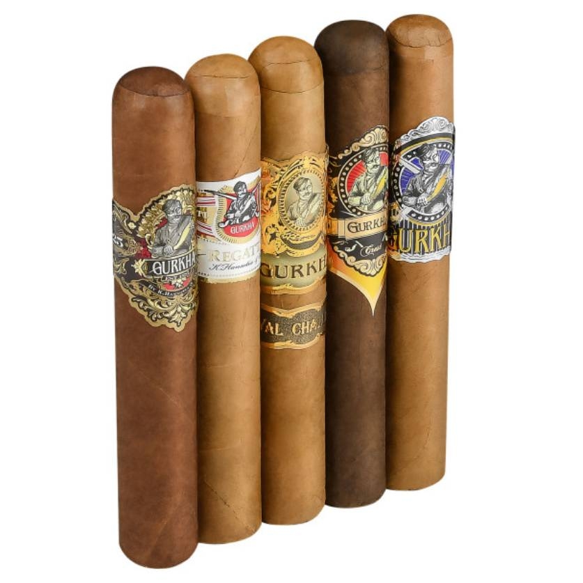 Five Gurkha cigars are laid side by side, each with a distinct decorative band showcasing the Gurkha brand logo and varying color schemes and designs.