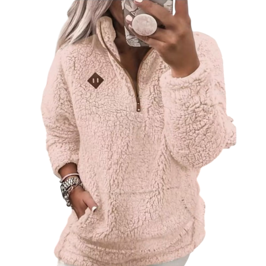 A person is wearing a pink sherpa fleece pullover with a quarter-zip design. The pullover has a brown patch on the chest, and the person has one hand in the pocket while taking a mirror selfie.