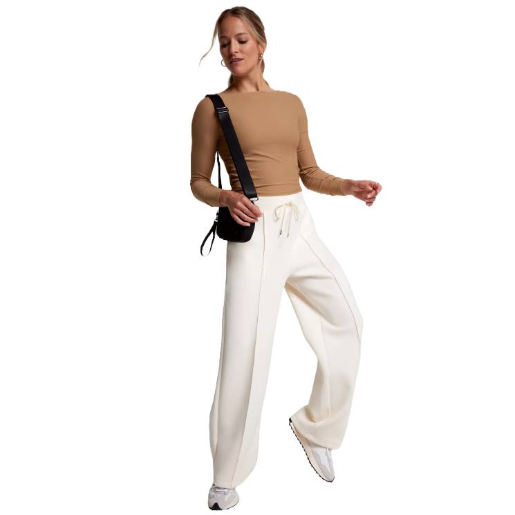 Calia Wide-Leg Pants are cream-colored with a drawstring waist, extra-wide legs, and a seam down the front of each leg. They offer a relaxed fit and casual style.