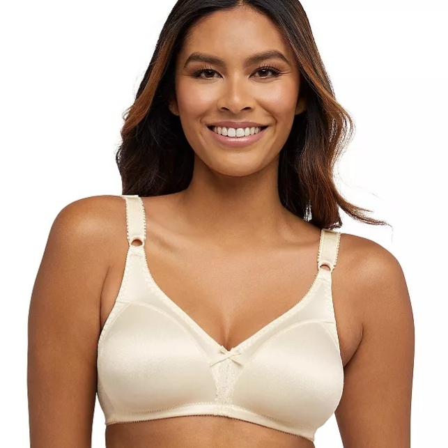 A woman is wearing a beige bra with wide straps and a subtle design, featuring a small bow at the front. The bra appears to be wireless and designed for comfort.