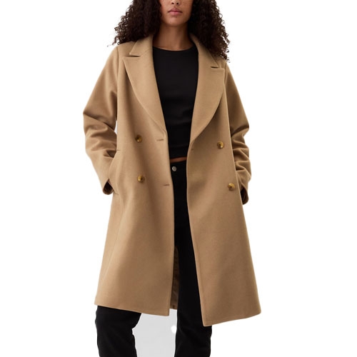 A woman is wearing a camel-colored, double-breasted wool coat with a black top and black pants.
