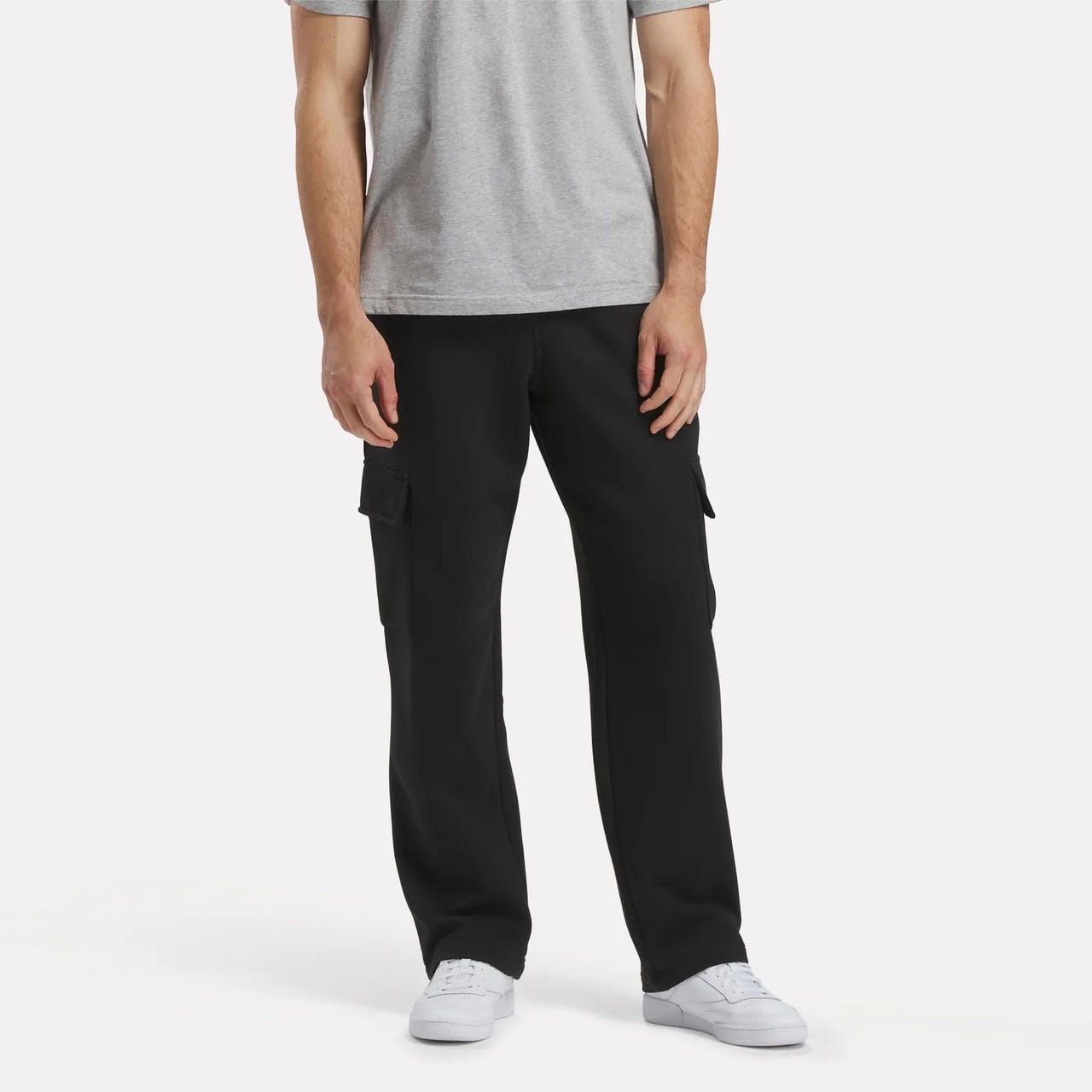 Black cargo pants with a relaxed fit featuring side pockets and a drawstring waist, paired with a grey t-shirt and white sneakers.