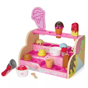 A toy ice cream shop set with a pink display stand, featuring various wooden ice cream cones, scoops, popsicles, a scooper, and cups.