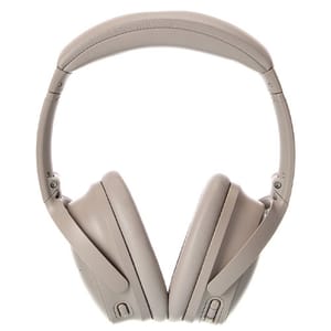 Noise-canceling over-ear headphones in a light tan color with adjustable padded headband and cushioned ear cups.