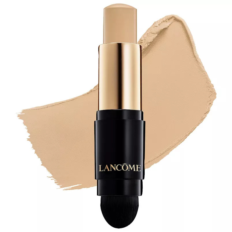 Lancôme makeup stick with black and gold packaging, featuring a foundation swipe and an attached brush for application.