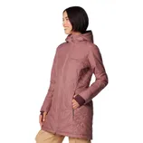 A woman is wearing a long, mauve Columbia jacket with a hood and diagonal quilted pattern. The jacket has zippered pockets and extends to mid-thigh.
