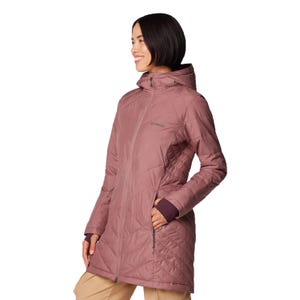 A woman is wearing a long, mauve Columbia jacket with a hood and diagonal quilted pattern. The jacket has zippered pockets and extends to mid-thigh.