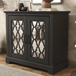 Black accent cabinet with mirrored doors featuring an intricate lattice design, two central handles, and decorative items on top, set on a wooden floor.
