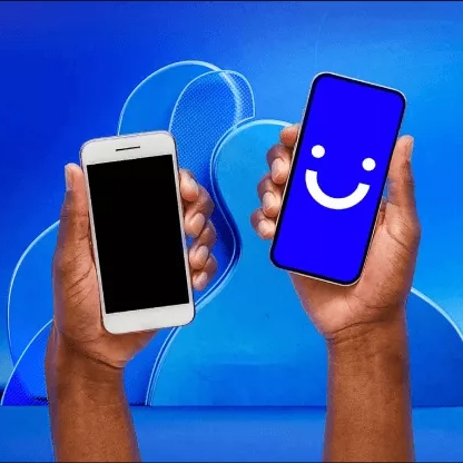 Two hands holding smartphones, one with a blank screen and the other displaying a happy face emoji.