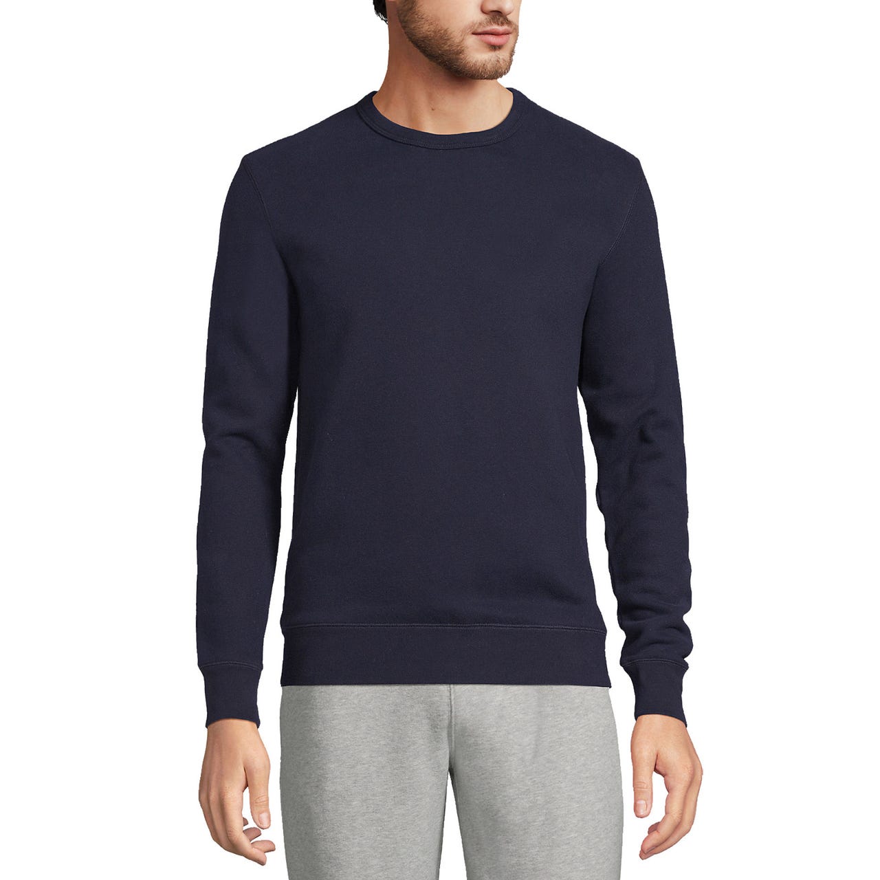 A man is wearing a navy blue crew-neck sweatshirt with ribbed cuffs and hem, paired with light gray sweatpants.