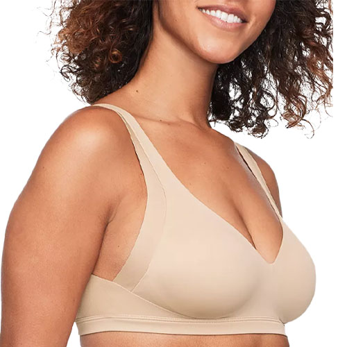 A woman wearing a beige seamless bra with wide shoulder straps.