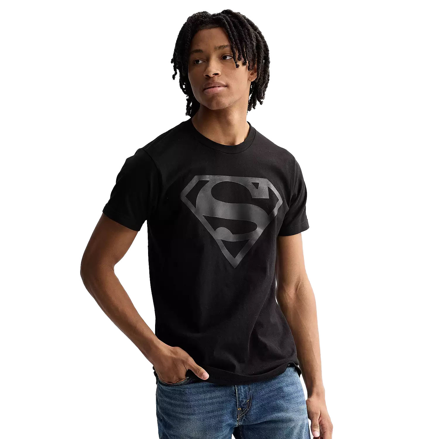 A person wearing a black t-shirt featuring a subtle, dark gray Superman logo, paired with blue jeans.