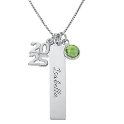 A silver necklace features three charms: the year \“2025,\“ a vertical bar with \“Isabella\“ inscribed, and a green gemstone pendant.