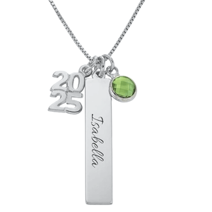 A silver necklace features three charms: the year \“2025,\“ a vertical bar with \“Isabella\“ inscribed, and a green gemstone pendant.