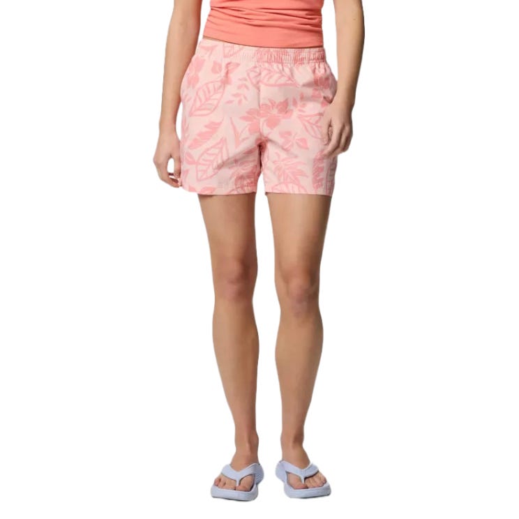 A person is wearing light pink floral-patterned shorts with pockets, paired with a matching tank top, and light blue flip-flops.