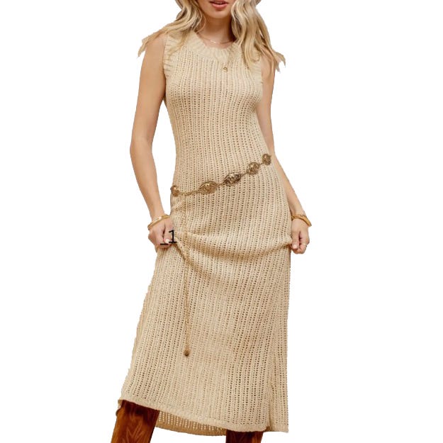 A model wears a sleeveless, beige knitted midi dress with a decorative waist belt, paired with brown knee-high boots.