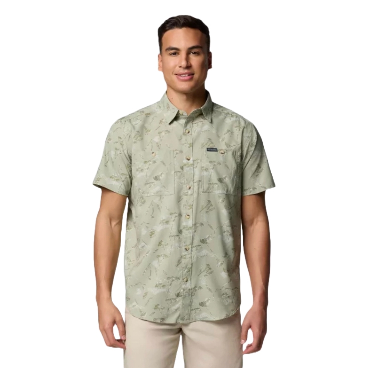 A man is wearing a light green, short-sleeve button-up shirt with a subtle nature-inspired print. The shirt features two chest pockets and a small label on one pocket.