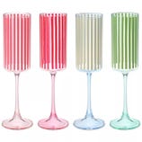 Four champagne flutes with vertical stripes in red, pink, beige, and green on clear stems.