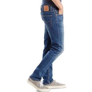 Levi's Slim Fit Jeans in a medium blue wash feature a classic five-pocket design, leather patch on the waistband, and a slightly tapered leg, paired with gray lace-up sneakers.