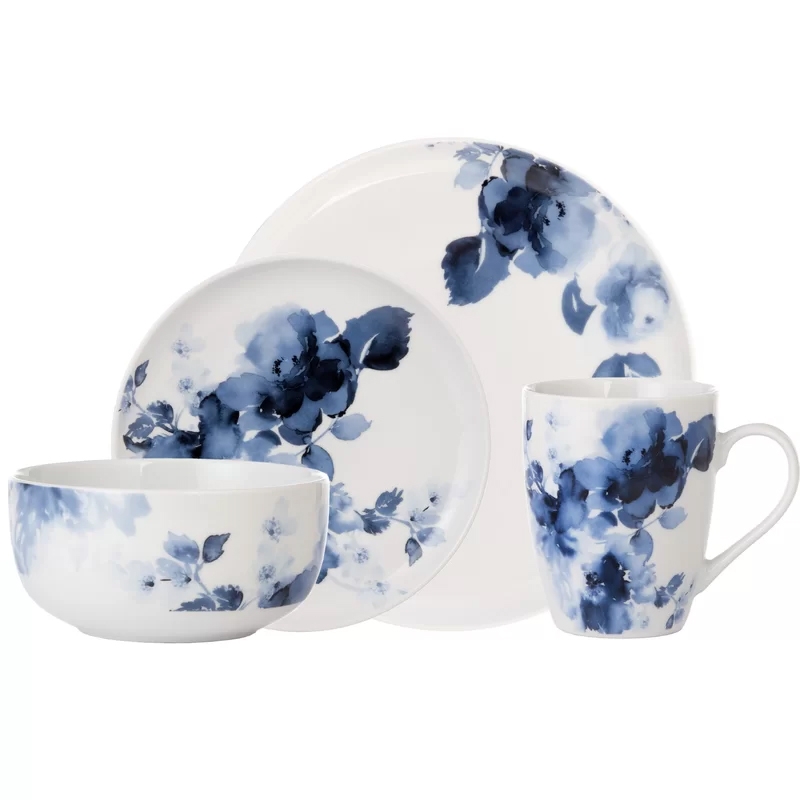 A dinnerware set featuring a white background with blue floral designs, including a dinner plate, salad plate, bowl, and mug.