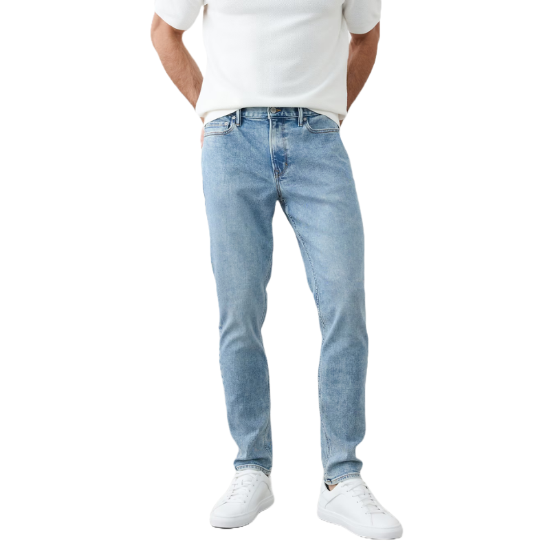 A person wearing light blue jeans and a white short-sleeve shirt paired with white sneakers.