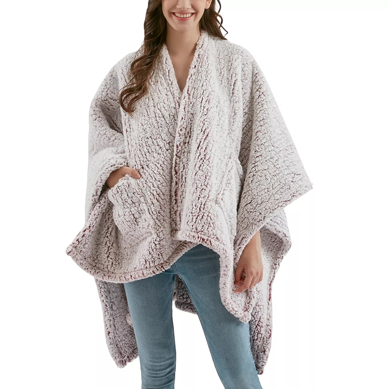 A person is wearing a plush, textured, light-colored poncho with wide sleeves and pockets, paired with light blue jeans.