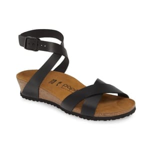 A black sandal with an ankle strap, buckle closure, and cork wedge sole, marked \“Papillio.\“