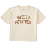 A cream-colored T-shirt with the words \“MASHED POTATOES\“ printed in brown, bold letters on the front.