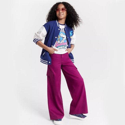 a girl with brown hair wearing blue letterman jacket and purple pants