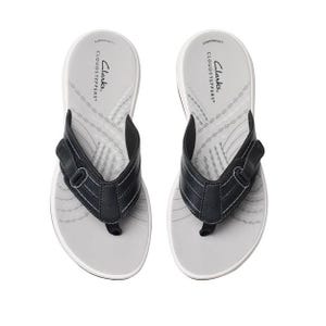 Pair of Clarks Cloudsteppers flip-flops with a white sole and black strap, featuring Cushion Soft technology.