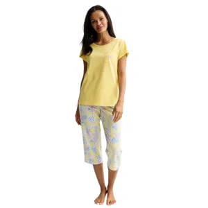 A woman is wearing a yellow short-sleeve top with a small pocket and floral-patterned capri pants.