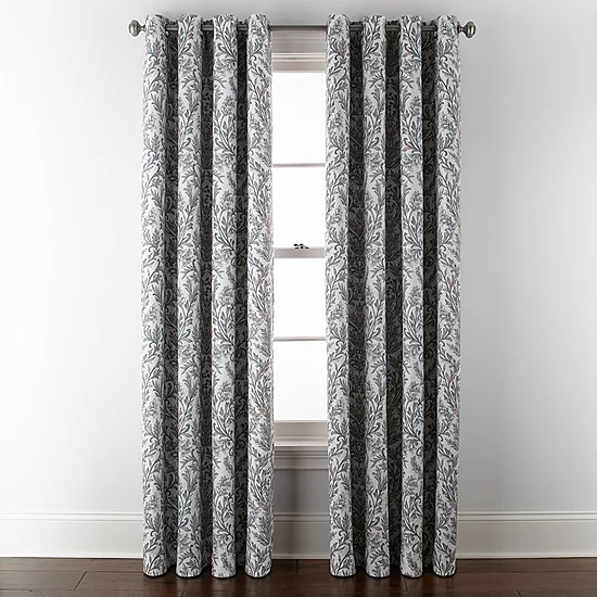 Gray and white patterned curtains hang from a metal rod, positioned in front of a window with a white frame.