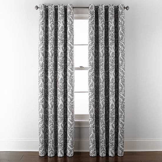 Gray and white patterned curtains hang from a metal rod, positioned in front of a window with a white frame.