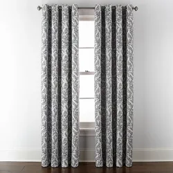 Gray and white patterned curtains hang from a metal rod, positioned in front of a window with a white frame.