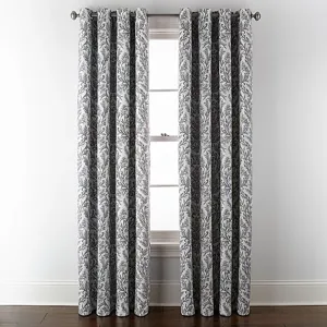 Gray and white patterned curtains hang from a metal rod, positioned in front of a window with a white frame.